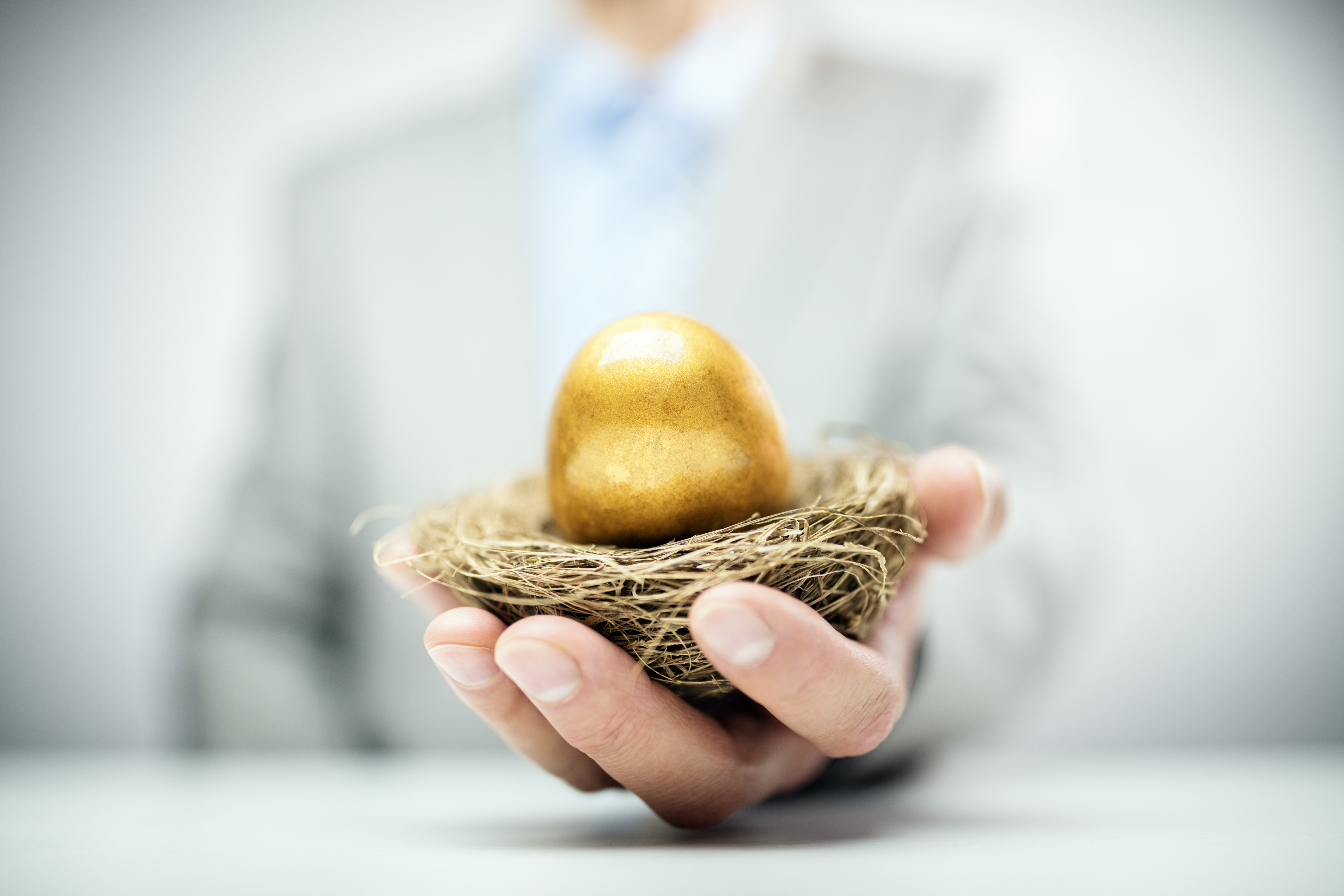 Retirement savings golden nest egg in a businessmans hand