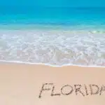 turquoise water and golden sand with shells and sea stars and "florida" written on it