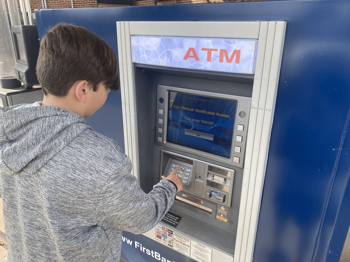 picture of my son taking cash from an ATM using his Greenlight debit card