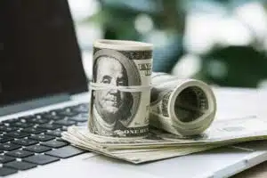 image of rolled cash on laptop to illustrate how to invest $10k