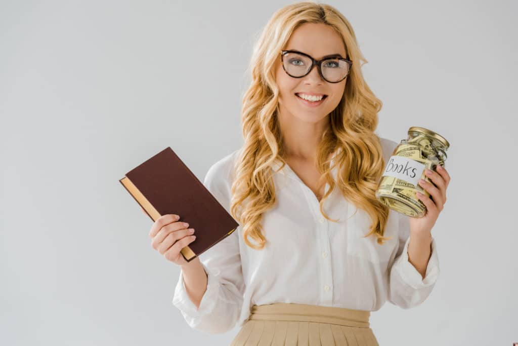 beautiful blond woman holding a jar of money and a book of business to demonstrate creating multiple income streams