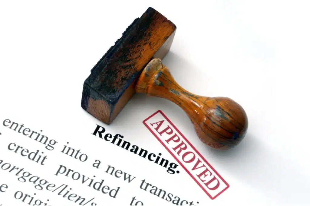 an Approved stamp laying across a piece of paper with the word refinancing printed on it