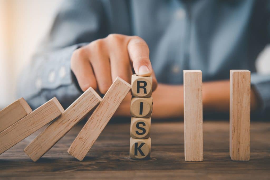 Person with their finger on a stack of blocks that spell out the word risk