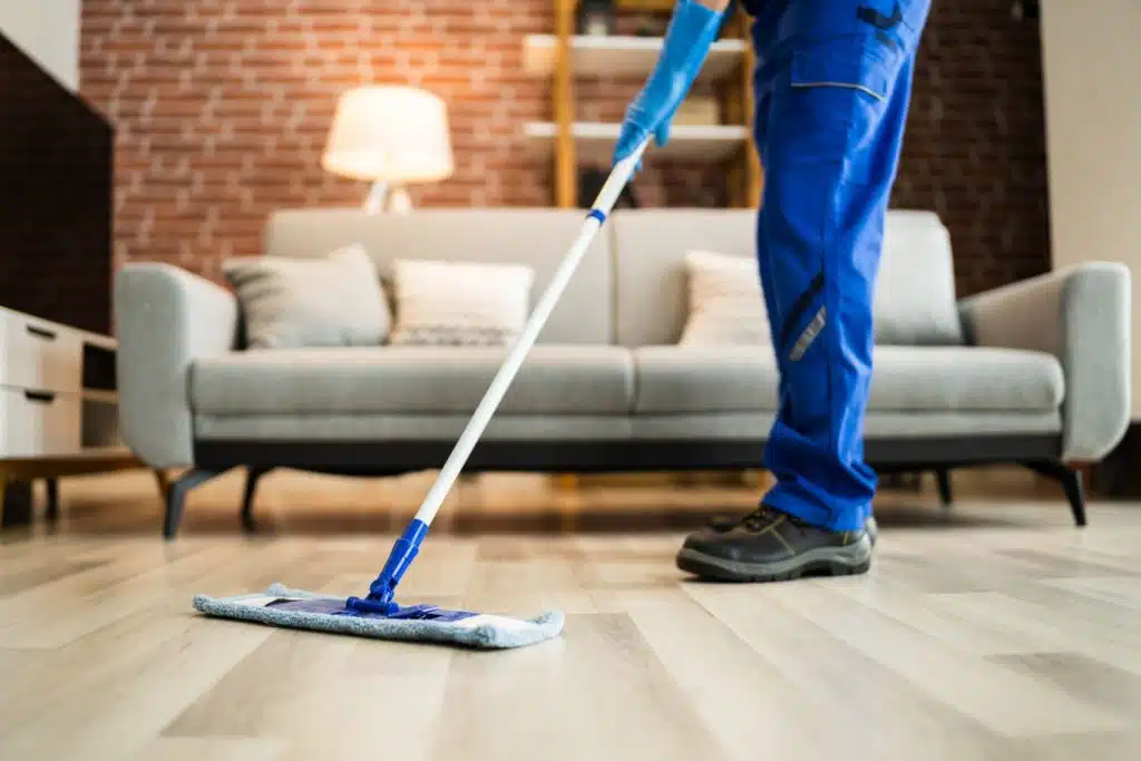 A person cleaning a living room floor with a Swiffer mop