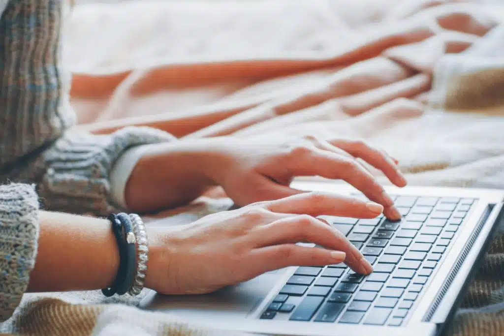 closeup of a woman's hands typing on a laptop