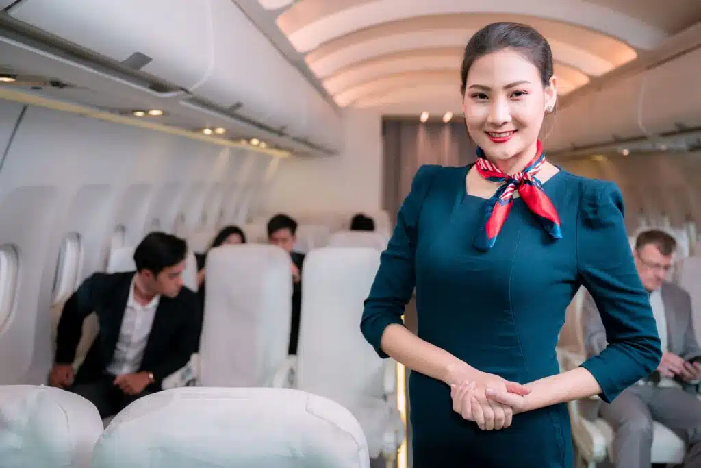 flight attendant smiling for the camera while standing inside an airplane